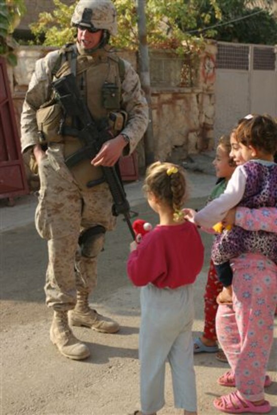 HADITHA, Iraq ? Corporal Scott K. Jepsen of Bridgewater, N.J. hands out toys and candy to children near the polling site of the Iraqi national elections here Dec. 15. Jepsen and Team 5, Detachment 2, 6th Civil Affairs Group, helped make it so that over 15,000 people voted in the Haditha area.