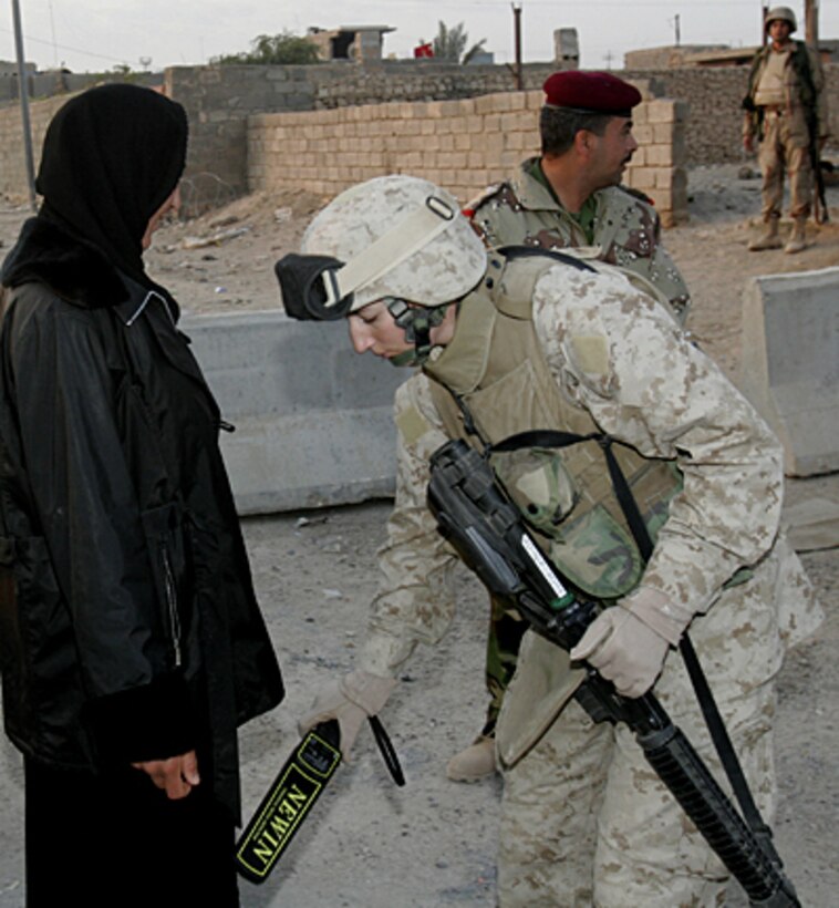 21-year-old St. Charles, Mich., native Cpl. Anne Hedrington uses a hand-held metal detector to screen a female Iraqi voter in Husaybah, Iraq, December 15. Islamic culture requires that Muslim women be searched only by women. The vote today is being held in order to elect a permanent Iraqi government.