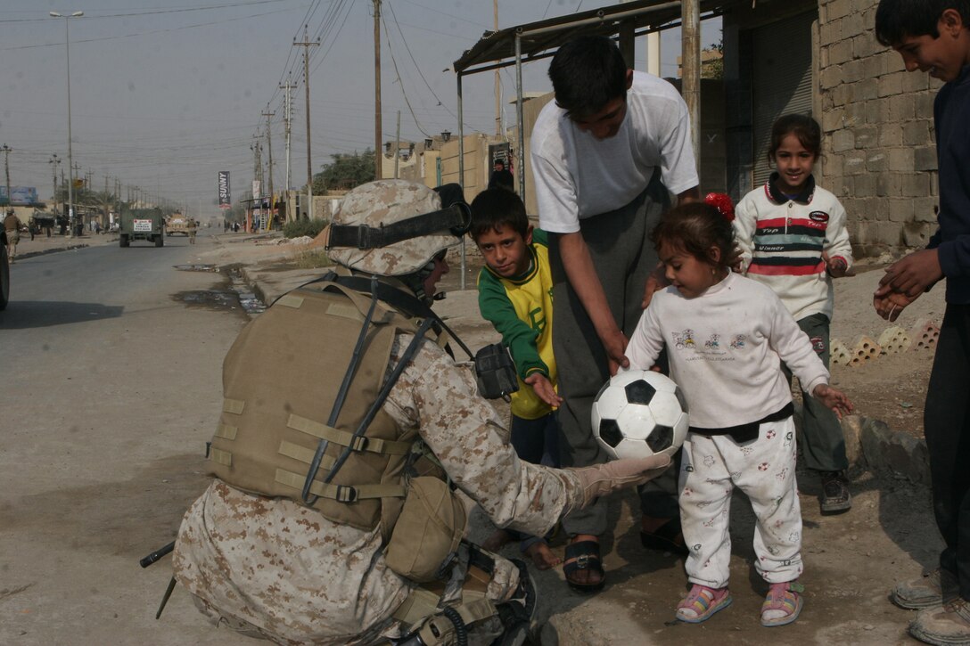 Lieutenant Col. Robert A. Sammel, Detachment 4 commander, 6th Civil Affairs Group, 2nd Marine Division, hands an Iraqi child a soccer ball during a patrol in Fallujah on the day of the elections. The soccer ball was one of many donated by the 7th and 8th grade students from Kailua Intermediate School, in Kailua, Hawaii.