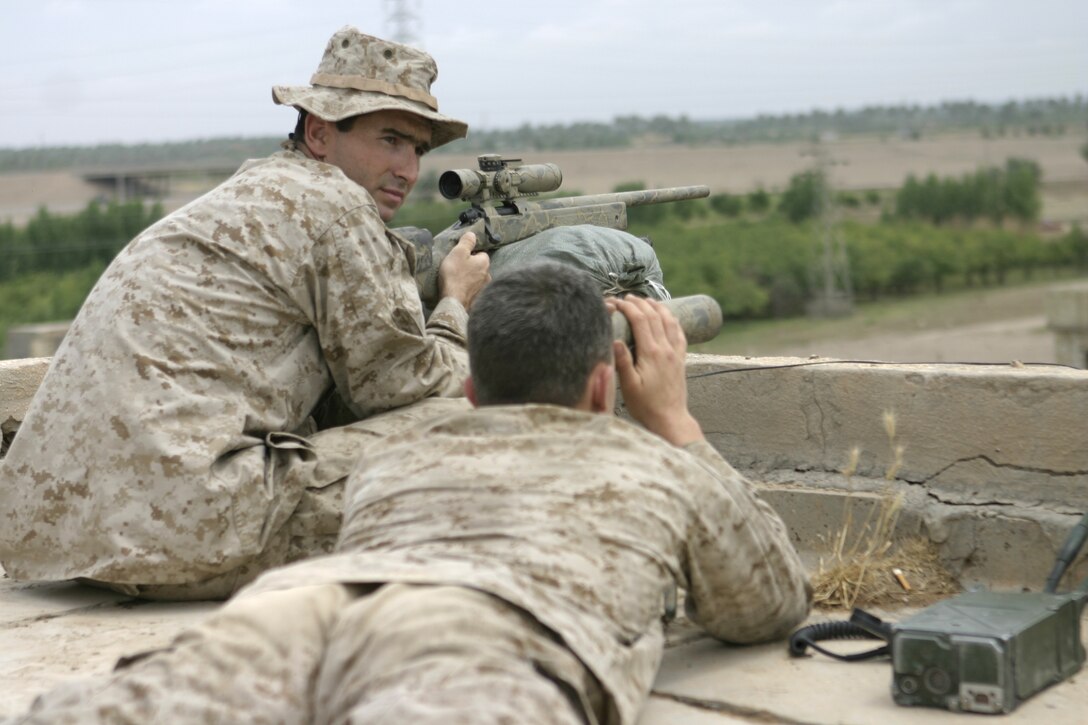 SAQLAWIYAH, Iraq - Sgt. Willis Davis, sniper team leader with STA (Surveillance, Target, and Acquisition) Platoon, Weapons Company, 1st Battalion, 6th Marine Regiment, left, and Cpl. Joseph R. Piner, assistant team leader, observe the terrain from a rooftop here April 26.  The snipers serve as the eyes and ears for the battalion, covertly keeping a watchful eye for suspicious activity, such as insurgents laying improvised explosive devices along convoy and patrol transit routes.