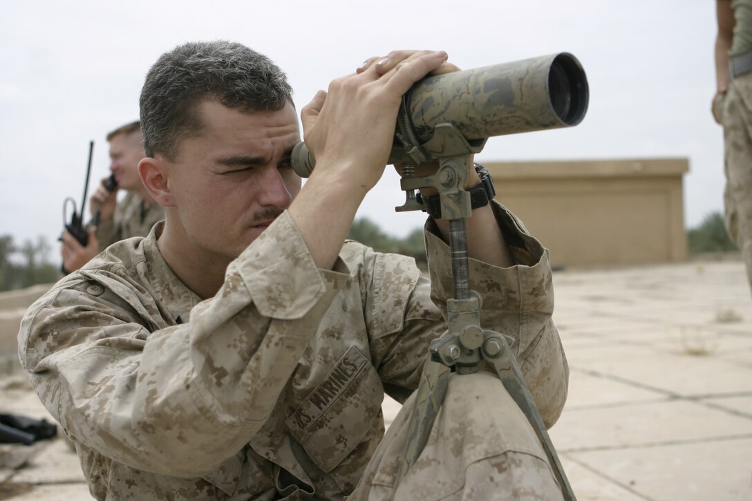 SAQLAWIYAH, Iraq - Cpl. Joseph R. Piner, assistant team leader with STA (Surveillance, Target, and Acquisition) Platoon, Weapons Company, 1st Battalion, 6th Marine Regiment, crouches atop a rooftop here April 26 and scans the horizons for insurgent activity.  The snipers serve as the eyes and ears for the battalion, covertly keeping a watchful eye for suspicious activity, such as insurgents laying improvised explosive devices along convoy and patrol transit routes.