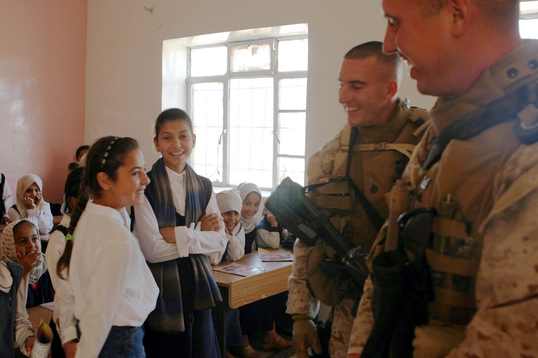 AL UBAYDI, Iraq (April 27, 2005)- Staff Sgt. Lee D. Chartier(left) and Lance Cpl. Christopher F. Tustin, both Marines with 3rd Battalion, 2nd Marine Regiment, Regimental Combat Team-2, make a joke about their drawing abilities to a class of Iraqi children during a school assessment here. Tustin, a Philadelphia native and 2000 Westchester University graduate, describes this experience as something he will never forget. Offical U.S. Marine Corps photo by Lance Cpl. Lucian Friel (RELEASED)