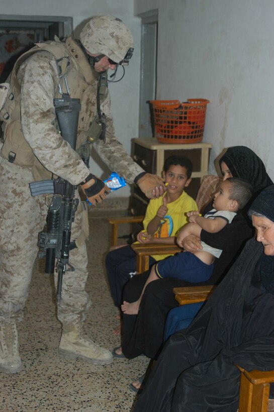 AR RAMADI, Iraq (May 16, 2005) -Corporal Christopher A. Hook, a rifleman and team leader with 2nd Squad, 3rd Platoon, Company A, 1st Battalion, 5th Marine Regiment, gives a young, Iraqi boy candy during a search mission here. The 26-year-old from Chelsea, Va., and his fellow warriors with 3rd Platoon conducted a cordon and search mission of a neighborhood with 15 New Iraqi Army soldiers. The three-hour joint-operation was geared toward keeping a military presence in area and establishing a positive relationship between Iraqi civilians and members of their own military. The Marines and their Iraqi counterparts executed the mission without incident. Photo by Cpl. Tom Sloan