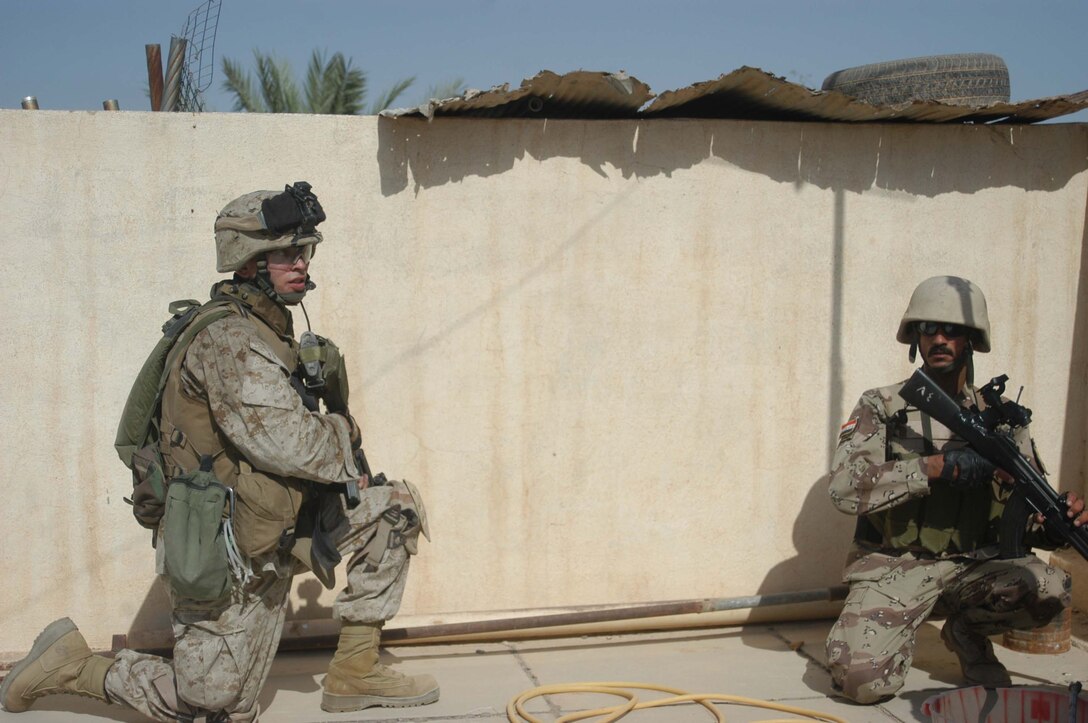 AR RAMADI, Iraq (May 16, 2005) - Corporal Kevin M. Spiwak, a team leader and grenadier with 1st Squad, 3rd Platoon, Company A, 1st Battalion, 5th Marine Regiment, and a New Iraqi Army (NIA) soldier provide security from the rooftop of a building here during a search mission. The 28-year-old from Rochester, N.Y., and his fellow warriors with 3rd Platoon conducted a cordon and search mission of a neighborhood with 15 NIA soldiers. The three-hour joint-operation was geared toward keeping a military presence in area and establishing a positive relationship between Iraqi civilians and members of their own military. The Marines and their Iraqi counterparts executed the mission without incident. Photo by Cpl. Tom Sloan