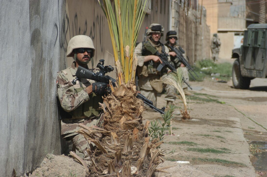 AR RAMADI, Iraq (May 16, 2005) - A New Iraqi Army (NIA) soldier crouches on the side of a street here during a mission with Marines with 3rd Platoon, Company A, 1st Battalion, 5th Marine Regiment. Fifteen NIA soldiers accompanied Marines with 3rd Platoon and, together, conducted a cordon and search mission of a neighborhood. The three-hour joint-operation was geared toward keeping a military presence in area and establishing a positive relationship between Iraqi civilians and members of their own military. The Marines and their Iraqi counterparts executed the mission without incident. Photo by Cpl. Tom Sloan