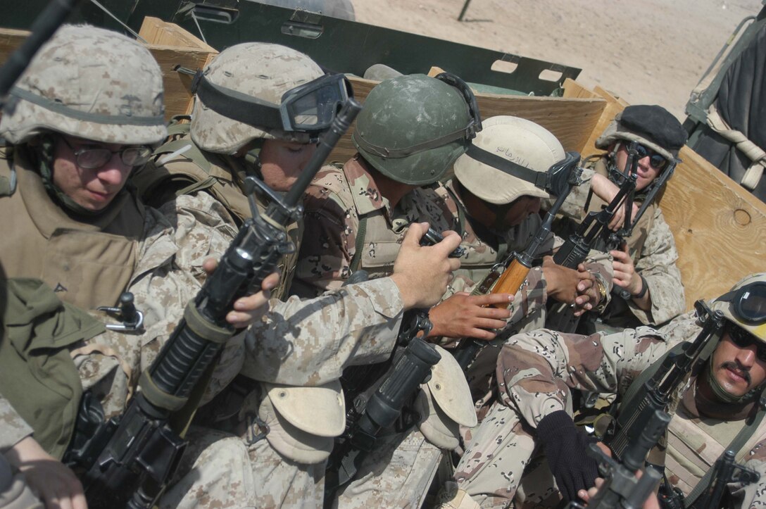 AR RAMADI, Iraq (May 16, 2005) -Marines with 3rd Platoon, Company A, 1st Battalion, 5th Marine Regiment, and New Iraqi Army (NIA) soldiers sit in the back of a 7-ton truck and get transported to their destination in the city here for a mission. Fifteen NIA soldiers accompanied Marines with 3rd Platoon and, together, conducted a cordon and search mission of a neighborhood. The three-hour joint-operation was geared toward keeping a military presence in area and establishing a positive relationship between Iraqi civilians and members of their own military. The Marines and their Iraqi counterparts executed the mission without incident. Photo by Cpl. Tom Sloan