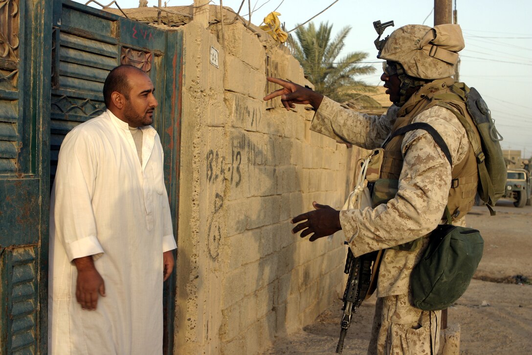 FALLUJAH, Iraq - Lance Cpl. Scott Pierre, a squad automatic gunner with 2nd Squad, 3rd Platoon, Company C, 1st Battalion, 6th Marine Regiment, speaks with a local citizen here July 16 during Operation Hard Knock.  The 21-year-old Fort Lauderdale, Fla. native worked alongside other battalion infantrymen and Iraqi Security Forces to search through a wired-off sector of Fallujah for weapons and insurgent activity, as well as gather census information on the populace.
