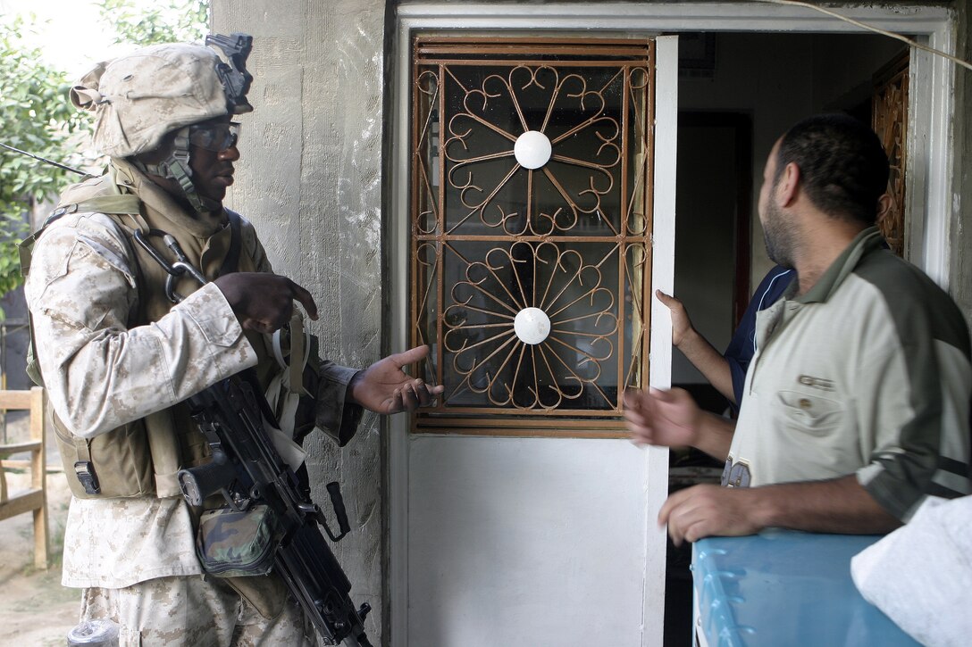 FALLUJAH, Iraq - Lance Cpl. Scott Pierre, a squad automatic gunner with 2nd Squad, 3rd Platoon, Company C, 1st Battalion, 6th Marine Regiment, asks a local citizen if he has any weapons inside his residence during Operation Hard Knock.  The 21-year-old Fort Lauderdale, Fla. native worked alongside other battalion infantrymen and Iraqi Security Forces to search through a wired-off sector of Fallujah for weapons and insurgent activity, as well as gather census information on the populace.