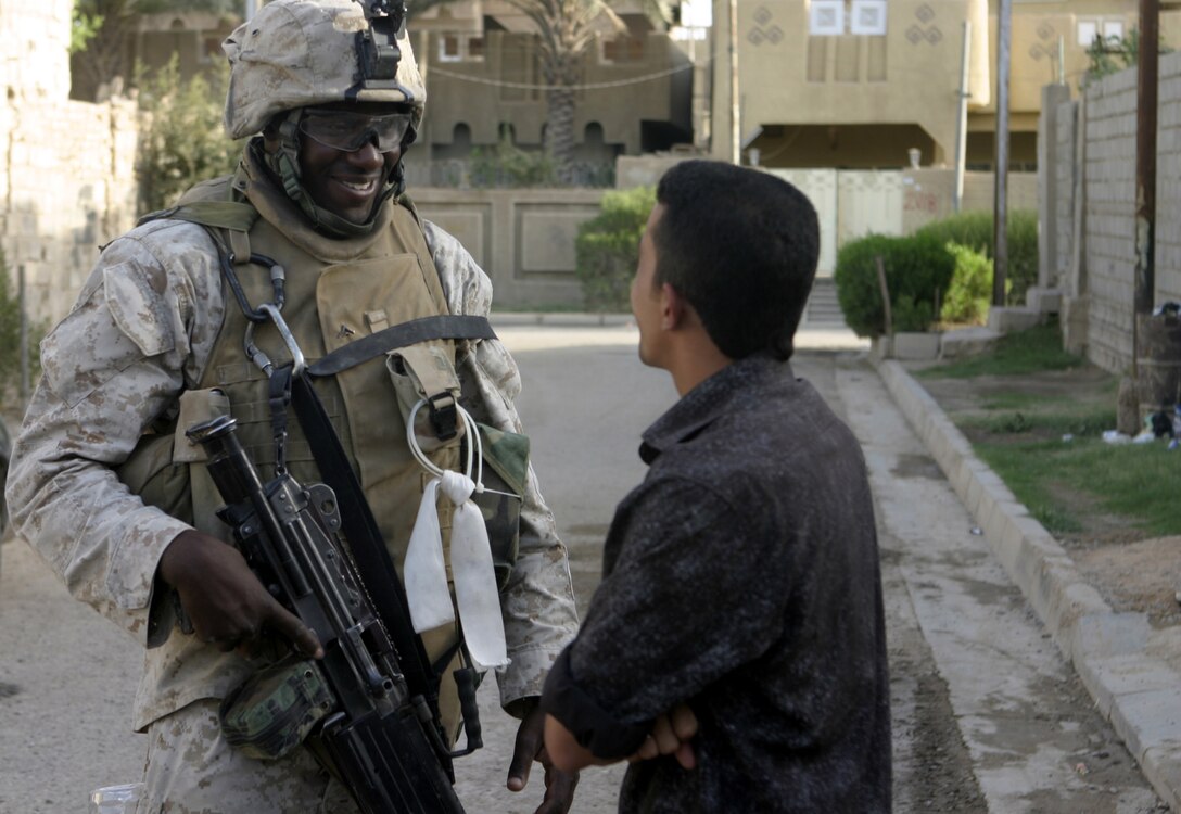 FALLUJAH, Iraq - Lance Cpl. Scott Pierre, a squad automatic gunner with 2nd Squad, 3rd Platoon, Company C, 1st Battalion, 6th Marine Regiment, speaks with a local citizen here July 16 during Operation Hard Knock.  The 21-year-old Fort Lauderdale, Fla. native worked alongside other battalion infantrymen and Iraqi Security Forces to search through a wired-off sector of Fallujah for weapons and insurgent activity, as well as gather census information on the populace.