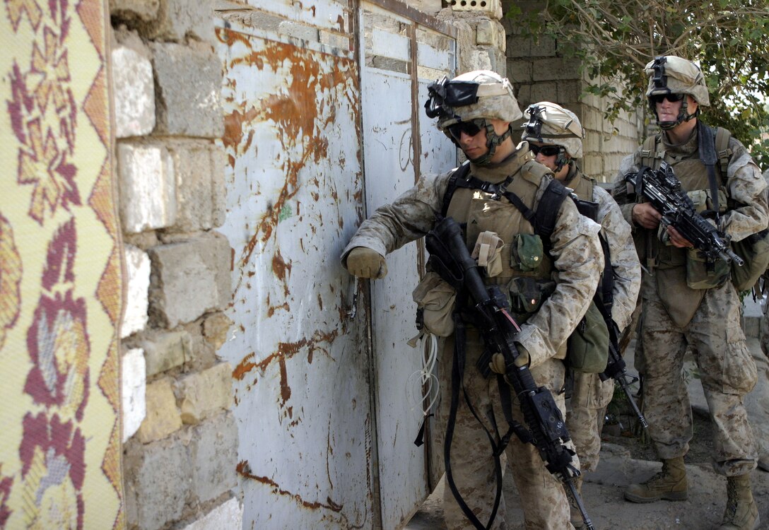 FALLUJAH, Iraq - Lance Cpl. Guido Filippone, an infantryman with 2nd Squad, 3rd Platoon, Company C, 1st Battalion, 6th Marine Regiment, knocks on a local home's door July 16 during Operation Hard Knock, as he and fellow squad members prepare to enter and search it.  Company C personnel worked alongside other battalion infantrymen and Iraqi Security Forces to search through a wired-off sector of Fallujah for weapons and insurgent activity, as well as gather census information on the populace.