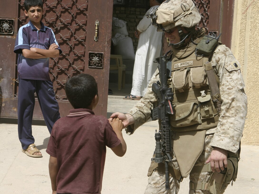 FALLUJAH, Iraq - Second Lieutenant Joseph Davis, 3rd Platoon commander, Company C, 1st Battalion, 6th Marine Regiment, interacts with a local child July 16 during Operation Hard Knock.  Company C personnel worked alongside other battalion infantrymen and Iraqi Security Forces to search through a wired-off sector of Fallujah for weapons and insurgent activity, as well as gather census information on the populace.