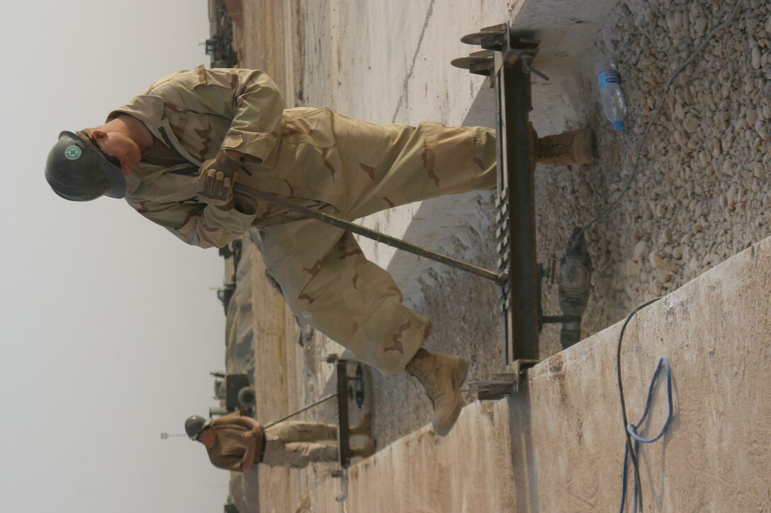 AL ASAD, Iraq ? Petty Officer 3rd Class James Hall, a steel worker with Naval Mobile Construction Battalion 24, drills holes in the concrete for the new joints the Seabees are working to put into the runway here. There are 100 joints that are going to be replaced by the end of the project. With two crews working day and night the Seabees have been completing an average of one joint per day.