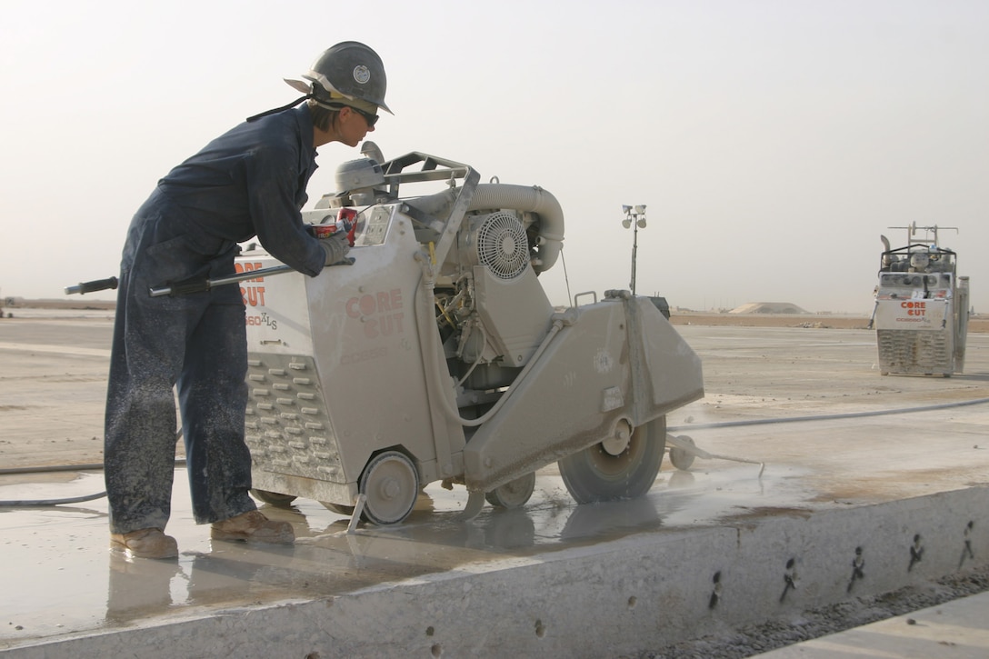 AL ASAD, Iraq ? Petty Officer 1st Class Jennifer Vann, a steel worker with Naval Mobile Construction Battalion 24, uses a concrete saw to cut a section of the runway here out so that it may be replaced. Vann is one of the Seabees who works the day shift for the runway reconstruction project scheduled to take the duration of their deployment here.