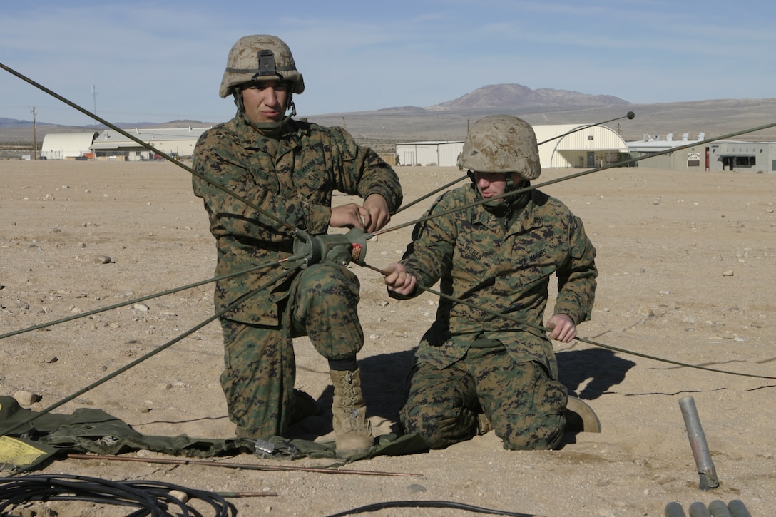MARINE CORPS AIR-GROUND COMBAT CENTER TWENTYNINE PALMS, Calif. -- Cpl. Oscar Garcia, a Marine with Communications Platoon, Headquarters and Service Company, 1st Battalion, 6th Marine Regiment, helps a fellow Marine set up an OE-254 communications antenna.  Garcia and his Marines are participating in a Revised Combined Arms Exercise here conducting scenarios they will perform during their upcoming deployment to Iraq in March.