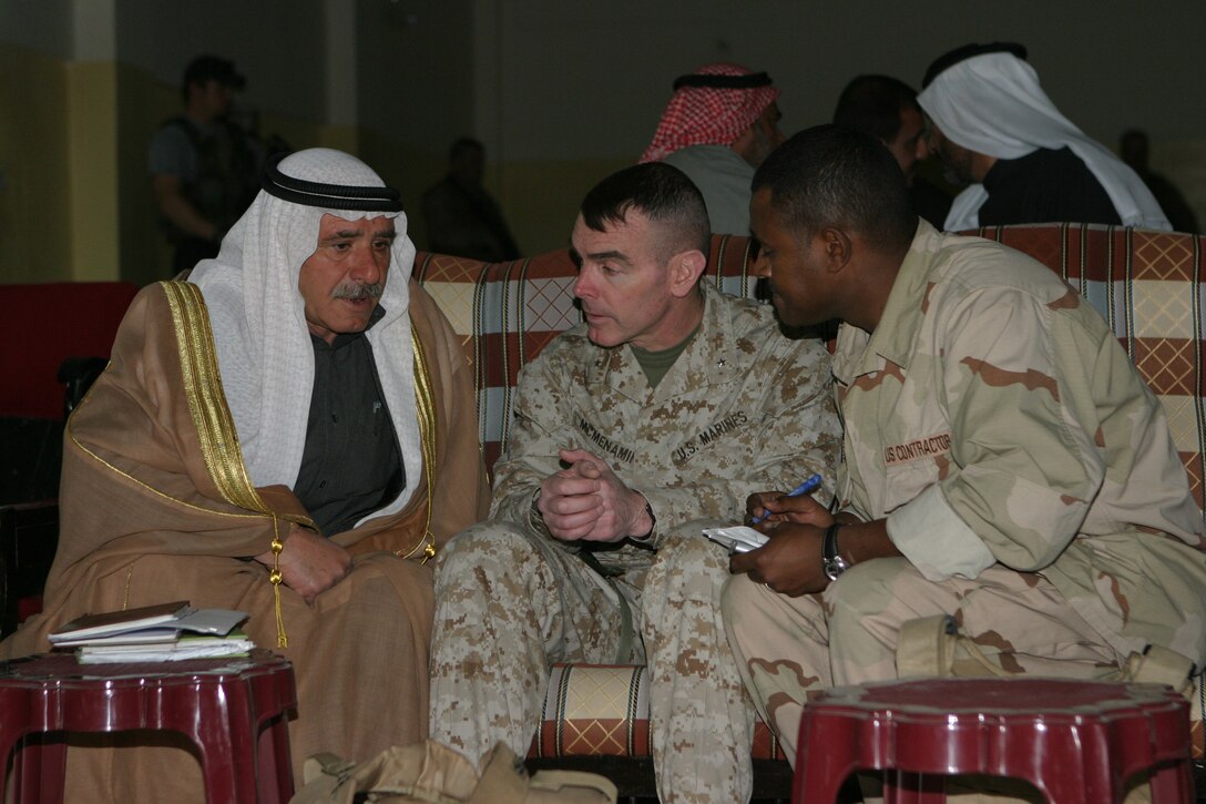 The 2d Marine Division's Assistant Division Commander, Brig. Gen. Joseph J. McMenamin talks with a member of the Al Anbar Provincial Council with the assistance of a translator at the Provincial Capital Building here during the councils first meeting. The officials elected to represent the Al Anbar Province invited McMenamin to attend their first meeting so that he could see the progress being made in the province.