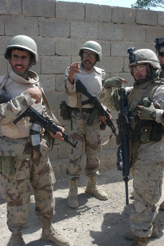 AR RAMADI, Iraq (April 17, 2005) - Corporal Richard A. Gutierrez, a team leader, with 3rd Squad, 3rd Platoon, Company C, 1st Battalion, 5th Marine Regiment, points to where he wants two members of the Iraqi Intervention Forces to be in his fire team during a patrol here. Fifteen IIF members accompanied Marines with 3rd Platoon, Company C, 1st Battalion, 5th Marines, and, together, conducted a combat patrol. The three-hour joint-mission was geared towards fine-tuning the IIF members' patrolling techniques by providing them with hands-on training in a combat environment. The 23-year-old Salinas, Calif., native and other Marines with 3rd Platoon, Company C, 1st Battalion, 5th Marines, showed their IIF counterparts proper dispersion, how to post security and set up over watches and other patrolling fundamentals.  Photo by Cpl. Tom Sloan