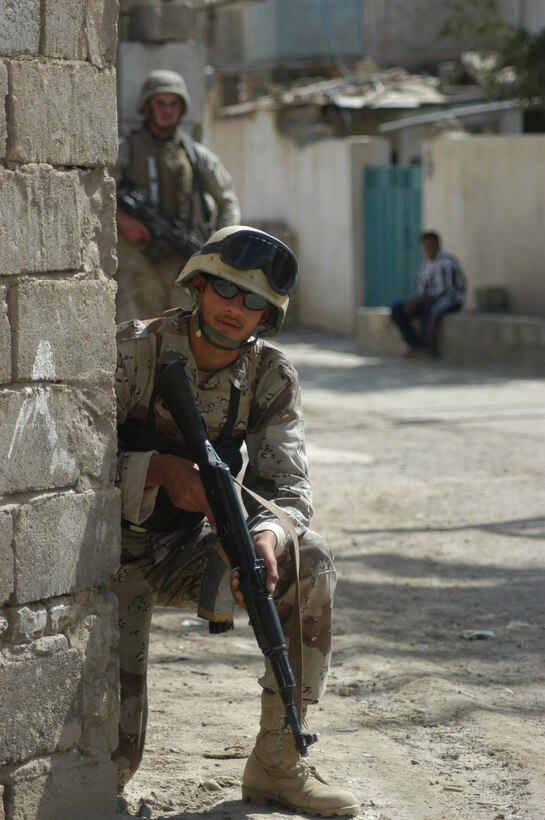 AR RAMADI, Iraq (April 17, 2005) - A member of the Iraqi Intervention Forces posts security from behind a brick wall during a patrol through the city here. A Marine with 3rd Platoon, Company C, 1st Battalion, 5th Marine Regiment, stands close behind and backs him up. Fifteen IIF members accompanied Marines with 3rd Platoon, Company C, 1st Battalion, 5th Marines, and, together, conducted a combat patrol. The three-hour joint-mission was geared towards fine-tuning the IIF members' patrolling techniques by providing them with hands-on training in a combat environment. Marines with 3rd Platoon, Company C, 1st Battalion, 5th Marines, showed their IIF counterparts proper dispersion, how to post security and set up over watches and other patrolling fundamentals. In the not so distant future, the IIF assume full responsibility of conducting security and stabilization operations when they are competent enough to successfully patrol the city on their own.  Photo by Cpl. Tom Sloan
