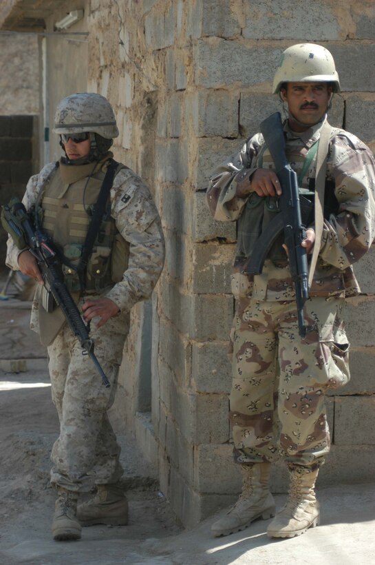 AR RAMADI, Iraq (April 17, 2005) - Corporal Cesar O. Hernandez, a team leader with 3rd Squad, 3rd Platoon, Company C, 1st Battalion, 5th Marine Regiment, and a member of the Iraqi Intervention Forces post security from a street corner together during a patrol here. Fifteen IIF members accompanied Marines with 3rd Platoon, Company C, 1st Battalion, 5th Marines, and, together, conducted a combat patrol. The three-hour joint-mission was geared towards fine-tuning the IIF members' patrolling techniques by providing them with hands-on training in a combat environment. Hernandez, a 21-year-old Burbank, Calif., native, and other Marines with 3rd Platoon, Company C, 1st Battalion, 5th Marines, showed their IIF counterparts proper dispersion, how to post security and set up over watches and other patrolling fundamentals. In the not so distant future, the IIF assume full responsibility of conducting security and stabilization operations when they are competent enough to successfully patrol the city on their own.  Photo by Cpl. Tom Sloan