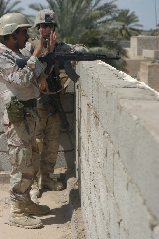 AR RAMADI, Iraq (April 17, 2005) - A member of the Iraqi Intervention Forces and Lance Cpl. Lance Cpl. Christopher C. Bennett, a rifleman with 3rd Squad, 3rd Platoon, Company C, 1st Battalion, 5th Marine Regiment, man an over watch position from the rooftop of a building here and provide security for their men on the ground during a patrol here. Fifteen IIF members accompanied Marines with 3rd Platoon, Company C, 1st Battalion, 5th Marines, and, together, conducted a combat patrol. The three-hour joint-mission was geared towards fine-tuning the IIF members' patrolling techniques by providing them with hands-on training in a combat environment. Bennett, a 24-year-old Dansville, Mich., native, and other Marines with 3rd Platoon, Company C, 1st Battalion, 5th Marines, showed their IIF counterparts proper dispersion, how to post security and set up over watches and other patrolling fundamentals. In the not so distant future, the IIF assume full responsibility of conducting security and stabilization operations when they are competent enough to successfully patrol the city on their own.  Photo by Cpl. Tom Sloan