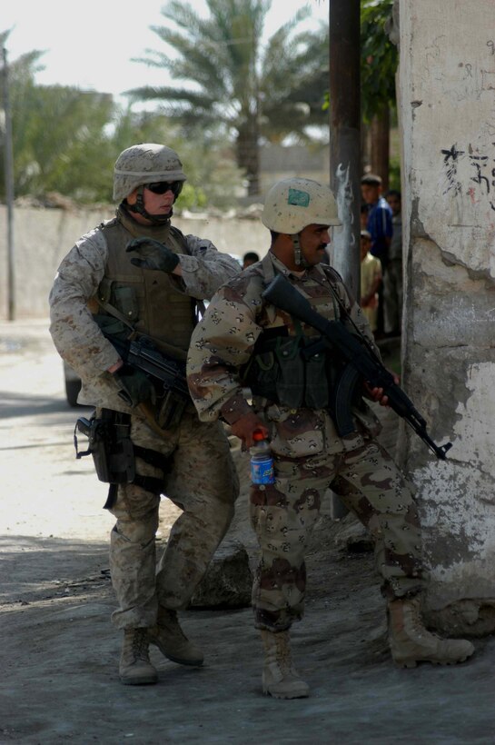AR RAMADI, Iraq (April 17, 2005) -Lance Cpl. Lance Cpl. Nathan A Favorit, a machine gunner with 3rd Squad, 3rd Platoon, Company C, 1st Battalion, 5th Marine Regiment, taps a member of the Iraqi Intervention Forces on the shoulder and relieves him from posting security on a street corner here during a patrol. Fifteen IIF members accompanied Marines with 3rd Platoon, Company C, 1st Battalion, 5th Marines, and, together, conducted a combat patrol. The three-hour joint-mission was geared towards fine-tuning the IIF members' patrolling techniques by providing them with hands-on training in a combat environment. Favorit, a 22-year-old Watertown, Wash., native, and other Marines with 3rd Platoon, Company C, 1st Battalion, 5th Marines, showed their IIF counterparts proper dispersion, how to post security and set up over watches and other patrolling fundamentals. In the not so distant future, the IIF assume full responsibility of conducting security and stabilization operations when they are competent enough to successfully patrol the city on their own.  Photo by Cpl. Tom Sloan
