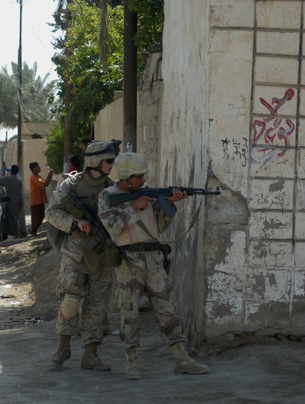 AR RAMADI, Iraq (April 17, 2005) -- Lance Cpl. Keith R. Campbell, an assault man with 3rd Squad, 3rd Platoon, Company C, 1st Battalion, 5th Marine Regiment, instructs a member of the Iraqi Intervention Forces on how to properly post security from a street corner during a patrol here. Fifteen IIF members accompanied Marines with 3rd Platoon, Company C, 1st Battalion, 5th Marines, and, together, conducted a combat patrol. The three-hour joint-mission was geared towards fine-tuning the IIF members' patrolling techniques by providing them with hands-on training in a combat environment. Campbell, a 19-year-old Littleton, Colo., native and other Marines with 3rd Platoon, Company C, 1st Battalion, 5th Marines, showed their IIF counterparts proper dispersion, how to post security and set up over watches and other patrolling fundamentals. In the not so distant future, the IIF assume full responsibility of conducting security and stabilization operations when they are competent enough to successfully patrol the city on their own.  Photo by Cpl. Tom Sloan