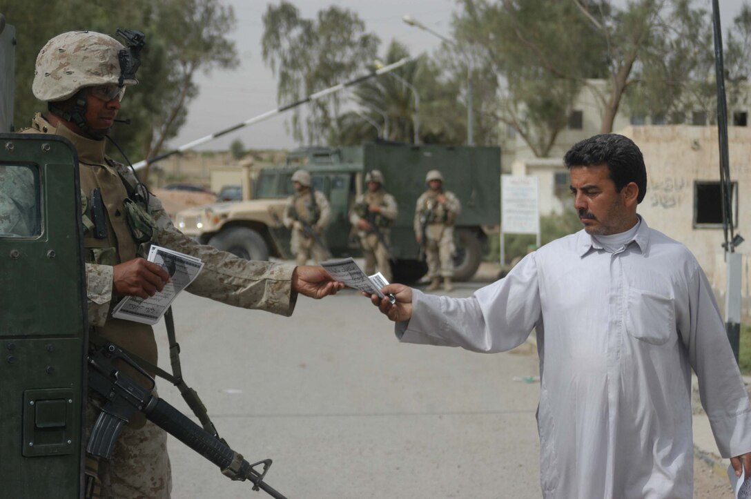 AR RAMADI, Iraq (May 17, 2005) -Corporal Jeno V. Hankerson, rifleman and police sergeant with Company C, 1st Battalion, 5th Marine Regiment, hands an Iraqi man a pro-Iraqi government flyer during a mission at the Maternity and Children's Hospital here. The 31-year-old from Cottonwood, Idaho, joined other Marines with the infantry battalion and soldiers from the Army's 2nd Brigade Combat Team and conducted an operation to improve medical care for residents of the city and foster good will toward coalition forces. The Marines and soldiers delivered four sea containers of medical supplies - valued at more than $500,000 - to the hospital. The supplies ranged from heart monitors and antibiotics to new bed sheets and bandages. Photo by: Cpl. Tom Sloan