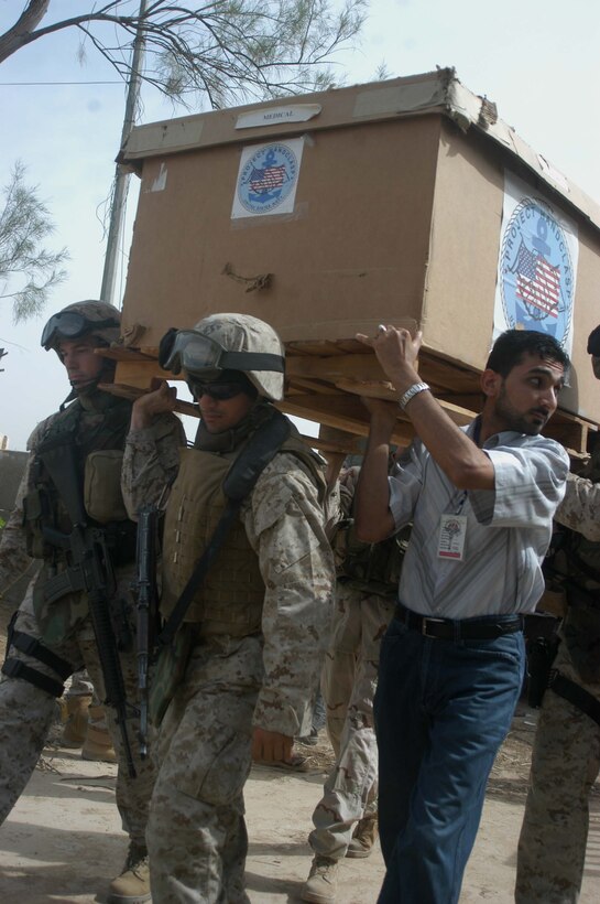 AR RAMADI, Iraq (May 17, 2005) - Major Benjamin B. Busch, (left) team leader of Team 1, Detachment 3, 5th Civil Affairs Group, which is in direct support of 1st Battalion, 5th Marine Regiment, and his interpreter help Iraqis carry a large box of medical supplies into the Maternity and Children's Hospital here during a mission. Marines with the 1st Battalion, 5th Marines, and soldiers from the Army's 2nd Brigade Combat Team and conducted an operation to improve medical care for residents of the city and foster good will toward coalition forces. The Marines and soldiers delivered four sea containers of medical supplies - valued at more than $500,000 - to the hospital. The supplies ranged from heart monitors and antibiotics to new bed sheets and bandages. Photo by: Cpl. Tom Sloan