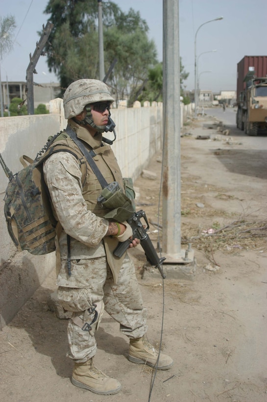 AR RAMADI, Iraq (May 17, 2005) - During a mission, Lance Cpl. Salvador Ramirez, a field radio operator with Company C, 1st Battalion, 5th Marine Regiment, provides security along a street in front of the Maternity and Children's Hospital here. The 21-year-old from Chicago joined other Marines with the infantry battalion and soldiers from the Army's 2nd Brigade Combat Team and conducted an operation to improve medical care for residents of the city and foster good will toward coalition forces. The Marines and soldiers delivered four sea containers of medical supplies - valued at more than $500,000 - to the hospital. The supplies ranged from heart monitors and antibiotics to new bed sheets and bandages. Photo by: Cpl. Tom Sloan
