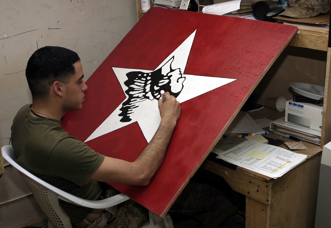 CAMP BAHARIA, Iraq - Lance Cpl. Luis Bonilla, an administration clerk with 1st Battalion, 6th Marine Regiment, puts the finishing touches on an 'Indian head' sign he created July 31 for display at the chapel here.  The 21-year-old Browns Mills, N.J. native helps resolve his fellow Marines' pay and promotion issues, and enjoys creating character sketches and painting during his free time.