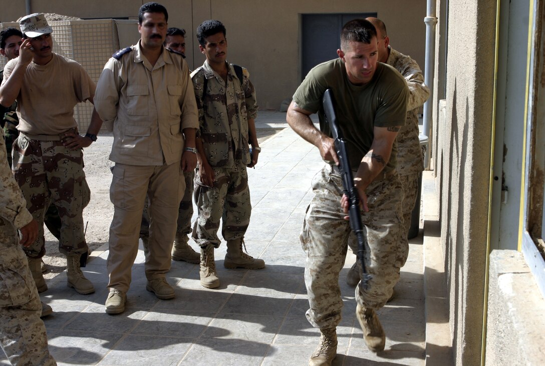 FALLUJAH, Iraq - Cpl. Brandon Connelly, an instructor with 1st Battalion, 6th Marine Regiment's Iraqi Security Forces training cadre, demonstrates proper room clearing procedures before a class of Iraqi troops here.  The 28-year-old Toms River, N.J. native and his seven teammates school dozens of Iraqi soldiers and policemen every month on topics such as first aid in combat, urban war fighting tactics, and weapons handling skills.