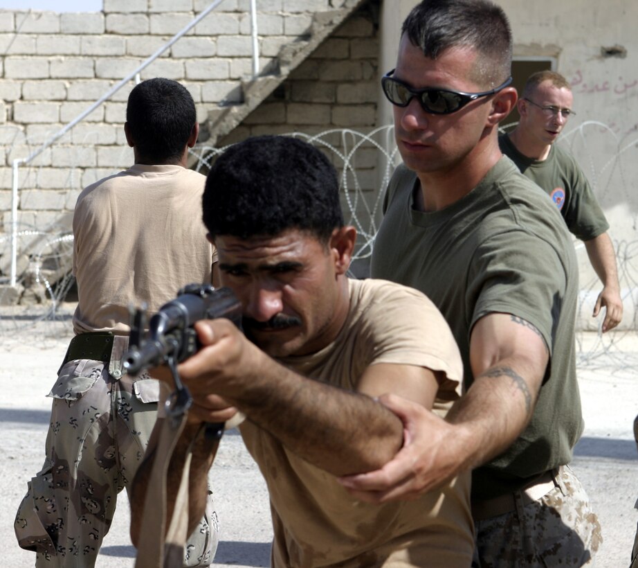 FALLUJAH, Iraq - Cpl. Brandon Connelly, an instructor with 1st Battalion, 6th Marine Regiment's Iraqi Security Forces training cadre, adjusts a soldier's firing stance during a class here Aug. 3.  The 28-year-old Toms River, N.J. native and his seven teammates school dozens of Iraqi soldiers and policemen every month on topics such as first aid in combat, urban war fighting tactics, and weapons handling skills.