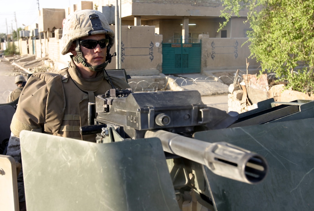FALLUJAH, Iraq - Lance Cpl. Jeremy Collins, a machine gunner with 2nd Combined Anti-Armor Team, Weapons Company, 1st Battalion, 6th Marine Regiment, mans his MK-19 automatic grenade launcher while providing security for fellow infantrymen patrolling the city streets Sept. 17.  Weapons Company personnel have been providing outer perimeter security during hundreds of patrols, raids and house-to-house search missions since arriving here in mid-March.