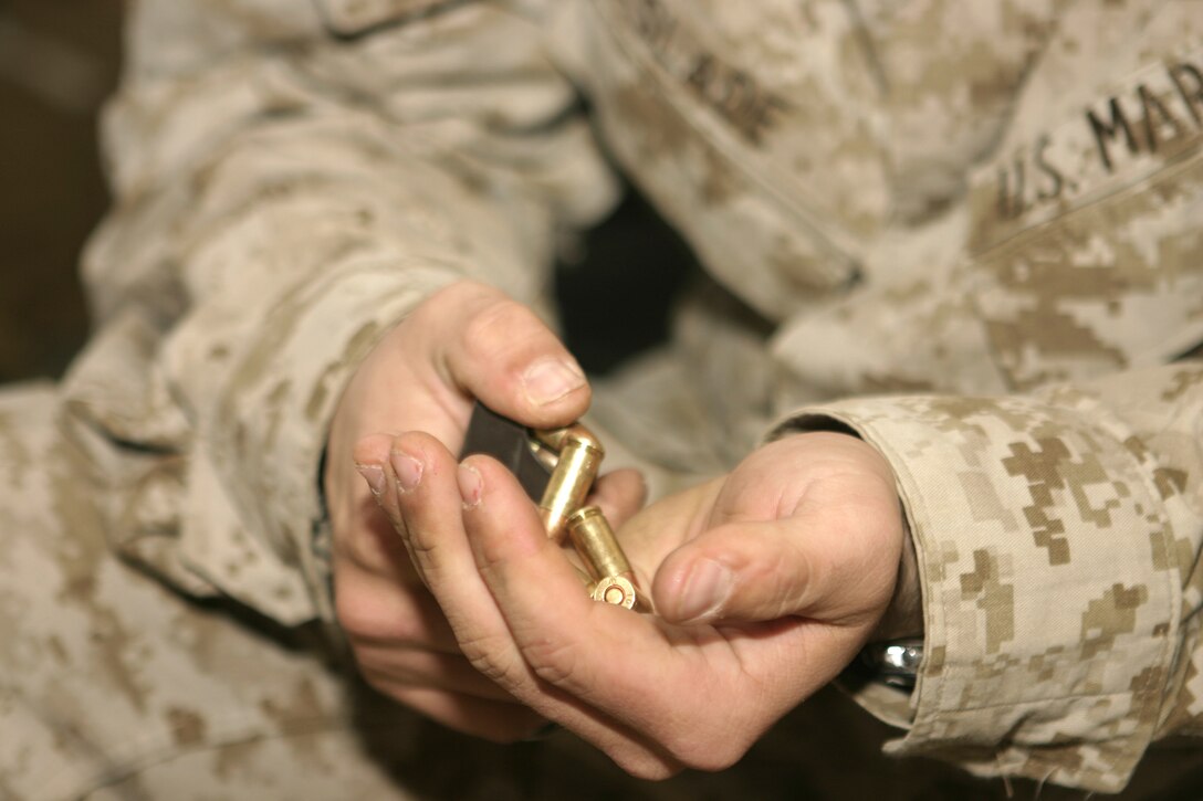 FALLUJAH, Iraq - Lance Cpl. Matthew L. Slade, Company A, 1st Battalion, 6th Marine Regiment armory custodian, empties a pistol magazine before attempting to fix it.  The 22-year-old Chandler, Ariz. native is currently deployed to Iraq, where he maintains accountability of his unit's rifles, machineguns and various other weapons.