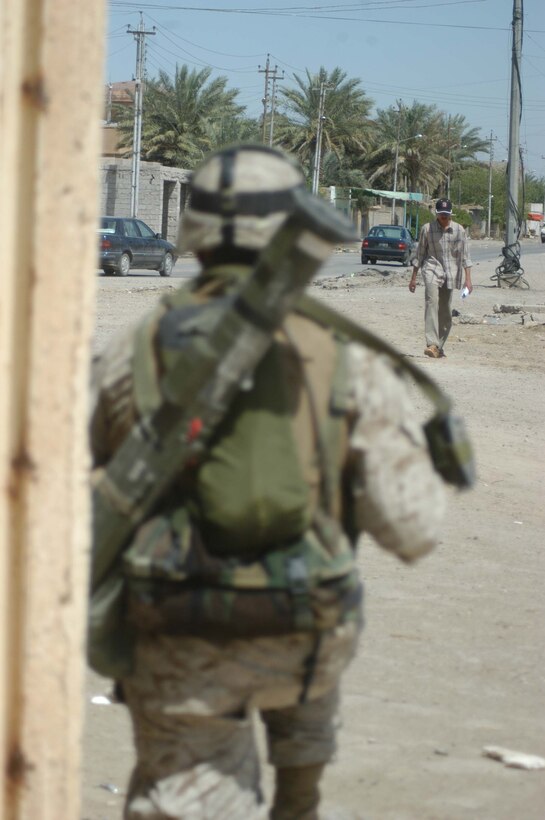 AR RAMADI, Iraq (April 18, 2005) -Lance Cpl. Angel R. Campos, a mortar man with 3rd Squad, 3rd Platoon, Company C, 1st Battalion, 5th Marine Regiment, posts security from a street corner and keeps vigilant watch on an Iraqi walking in the street ahead of him. Locals living in the southern outskirts of the city here have been known to harbor hatred toward Marines visiting their neighborhoods. Campos, 20-year-old from San Diego joined other Marines with 3rd Platoon, Company C, 1st Battalion, 5th Marines, in visiting an area where, just two weeks ago, they engaged insurgents in the biggest firefight they've had since deploying here in early March. Nothing happened during this patrol, however, and the warriors returned safely to their firm base, Camp Snake Pit. Photo by Cpl. Tom Sloan