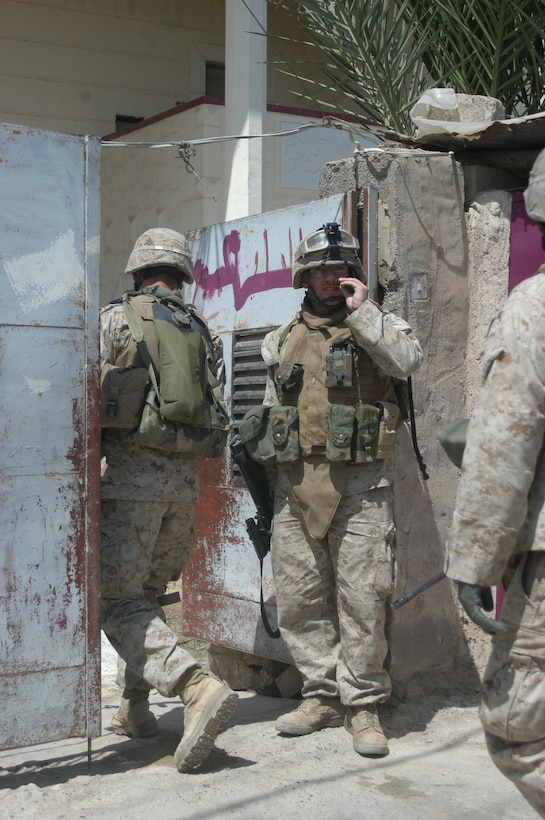 AR RAMADI, Iraq (April 18, 2005) -Corporal Patrick B. Finnigan, squad leader, 3rd Squad, 3rd Platoon, Company C, 1st Battalion, 5th Marine Regiment, talks on his radio as his Marines enter the yard of a residence here. The 30-year-old St. Louis native led his Marines and visited an area where, just two weeks ago, they engaged insurgents in the biggest firefight they've had since deploying here in early March. Nothing happened during this patrol, however, and the warriors returned safely to their firm base, Camp Snake Pit. Photo by Cpl. Tom Sloan
