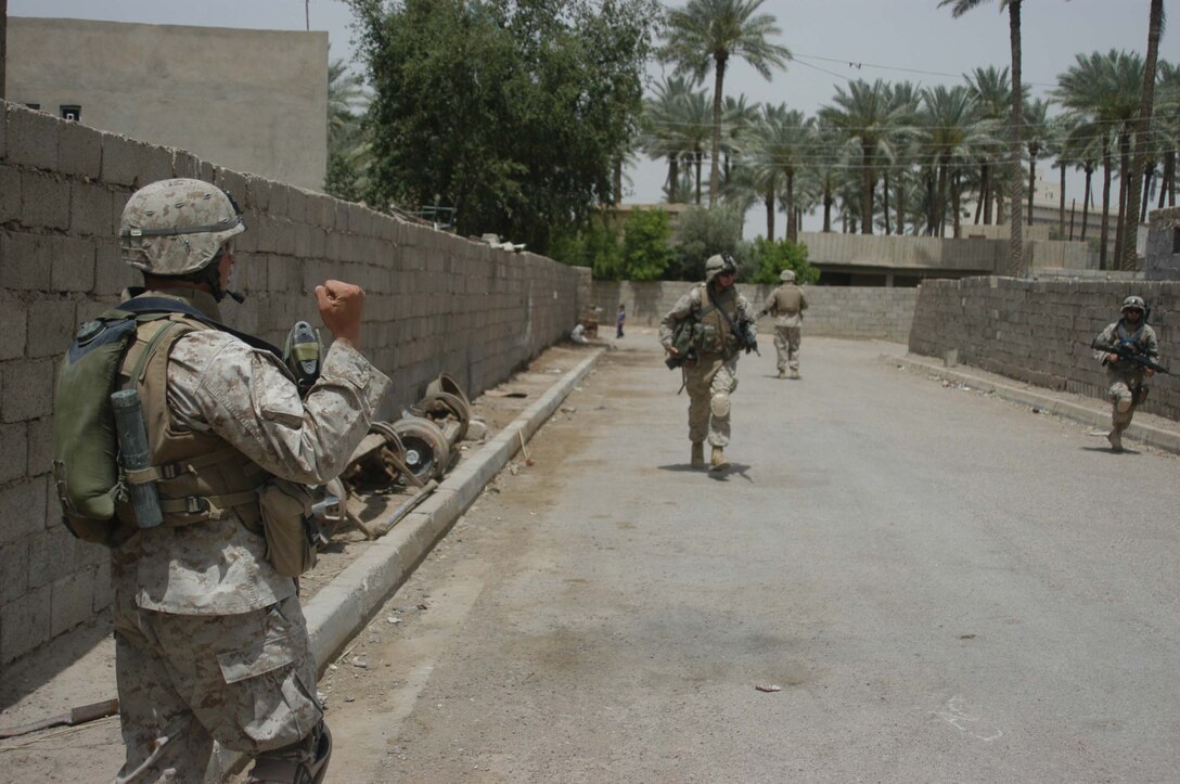 AR RAMADI, Iraq (May 15, 2005) - Lance Cpl. Josiah R. Hirsch, a rifleman and team leader with 2nd Squad, 2nd Platoon, Company B, 1st Battalion, 5th Marine Regiment, signals to his fellow Marines to "double time" during a combat foot patrol through the city here. The 19-year-old from Dublin, Calif., was made a team leader two months after his infantry battalion arrived in Iraq and began conducting security and stabilization operations in support of Operation Iraqi Freedom. The 2004 Valley Christian High School graduate has been in the Corps less than a year. Photo by: Cpl. Tom Sloan