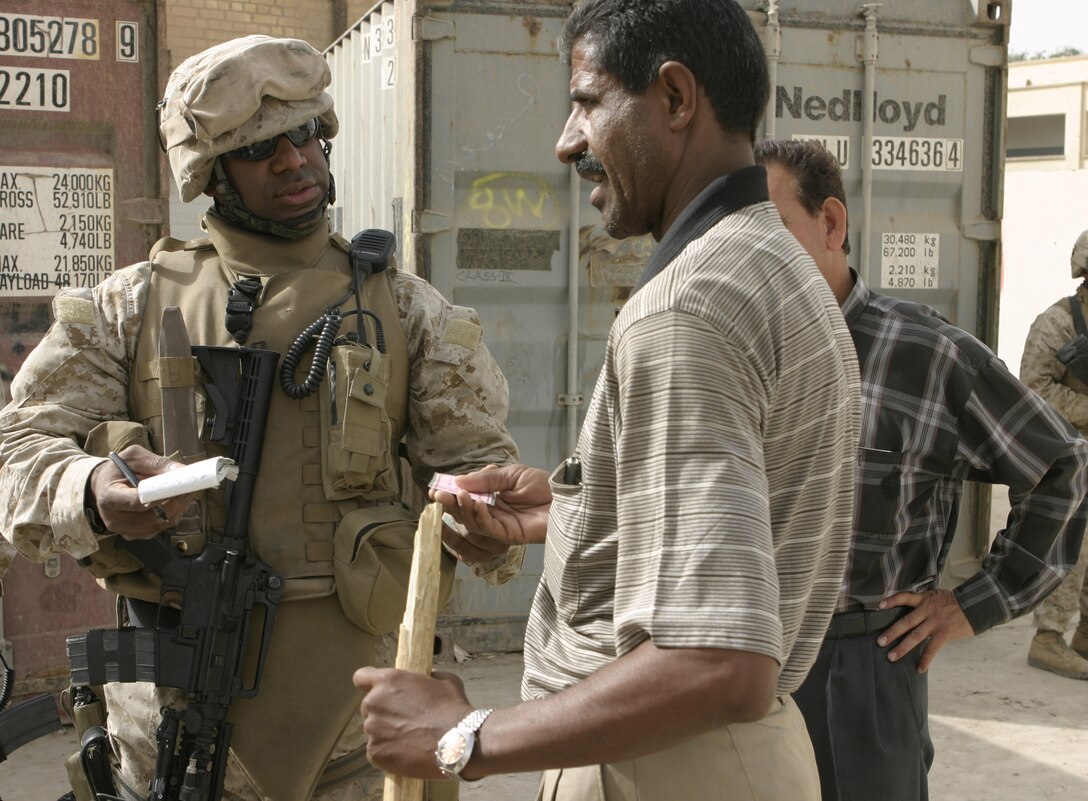 FALLUJAH, Iraq - Capt. Waheed U. Khan, Headquarters and Service Company, 1st Battalion, 6th Marine Regiment's company commander, speaks with an administrator outside a school May 18 to find out what supplies and facilities his students need.  Khan worked alongside Iraqi Security Forces to visit two local schools and distribute 59 desks.