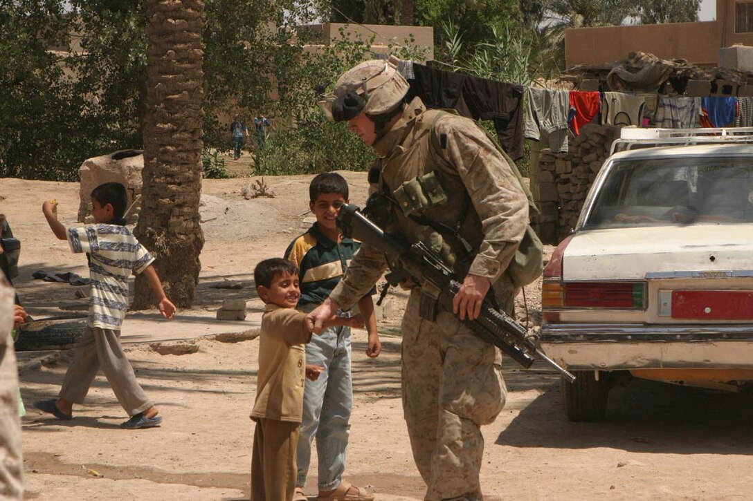 CAMP DELTA, Iraq -- Marines patrolling the streets during counter-indirect fire operations take the time to smile and say hello with the local children who come running up waving to the Marines.  Official U.S. Marine Corps photo by Lance Cpl. Athanasios L. Genos
