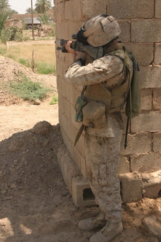 CAMP DELTA, Iraq -- The Marines stop to place posters on walls and on trees throughout the local communities while being watched having cover provided from their fellow Marines.  Official U.S. Marine Corps photo by Lance Cpl. Athanasios L. Genos