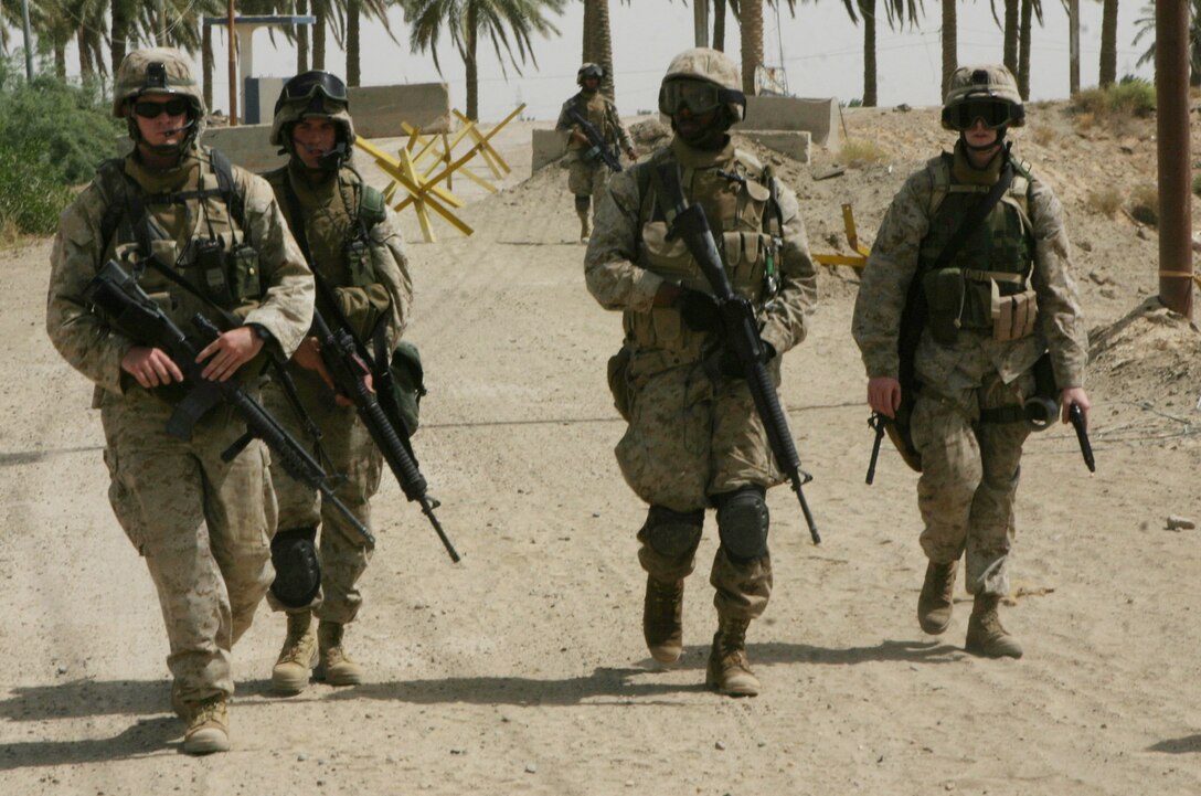 CAMP BLUE DIAMOND, AR RAMADI, Iraq - Members of the band walk back through the gate after a patrol outside the camp's walls, July 15, looking for insurgent weapons or encampments.  The Camp Lejeune, N.C.-based band, normally accustomed to the business of playing ceremonial military music for changes of command and the Marine Corps birthday ball, changed their focus more than a year ago when they found out they would become headquarters battalion's main defense against insurgent attacks.  U.S. Marine Corps photo by Sgt. Stephen D'Alessio (RELEASED)