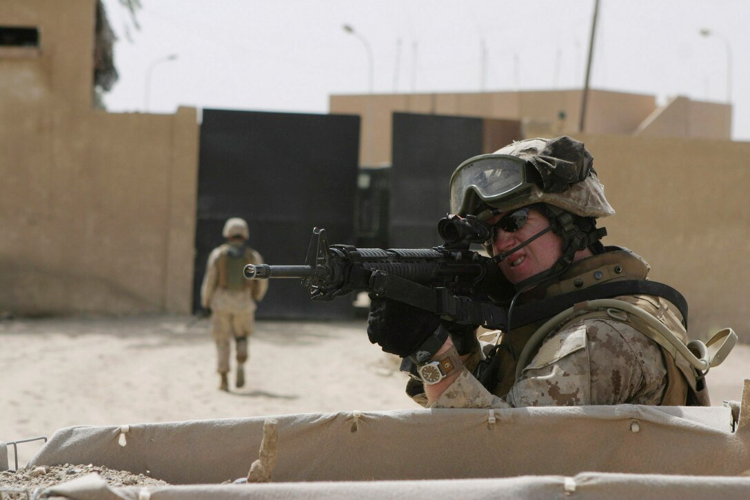 CAMP BLUE DIAMOND, AR RAMADI, Iraq - A member of the camp's guard force scans the perimeter as his patrol formation walks back through the gate after a search outside the camp's walls, July 15, looking for insurgent weapons or encampments.  The Camp Lejeune, N.C.-based band, normally accustomed to the business of playing ceremonial military music for changes of command and the Marine Corps birthday ball, changed their focus more than a year ago when they found out they would become headquarters battalion's main defense against insurgent attacks.  U.S. Marine Corps photo by Sgt. Stephen D'Alessio (RELEASED)