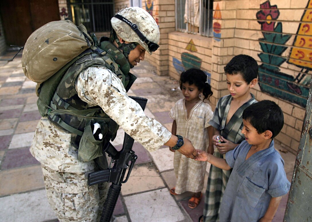 Hit, Al Anbar, Iraq (August 4, 2005)--Minneapolis, Minn., native, Hospitalman 3rd Class Chan Vang, 32, with Company "I", 3rd Battalion, 25th Marine Regiment gives local children candy during a patrol stop. (Official USMC Photo by Corporal Ken Melton)