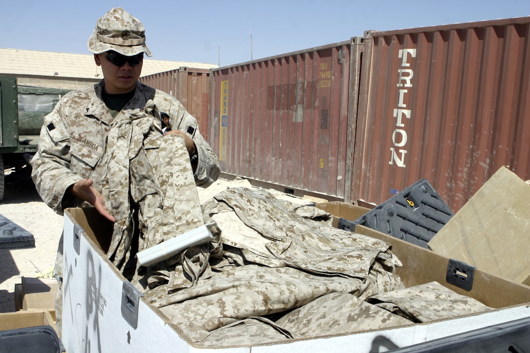 CAMP FALLUJAH, Iraq - Lance Cpl. Roy L. Gamboa, a supply administration clerk with 1st Battalion, 6th Marine Regiment, sifts through a box of camouflage utility uniforms destined to be issued out to his unit's personnel.  The 28-year-old Agat, Guam native and his team of supply Marines store and keep track of millions of dollars worth of equipment their battalion's infantrymen use to conduct counterinsurgency operations in and around Fallujah.