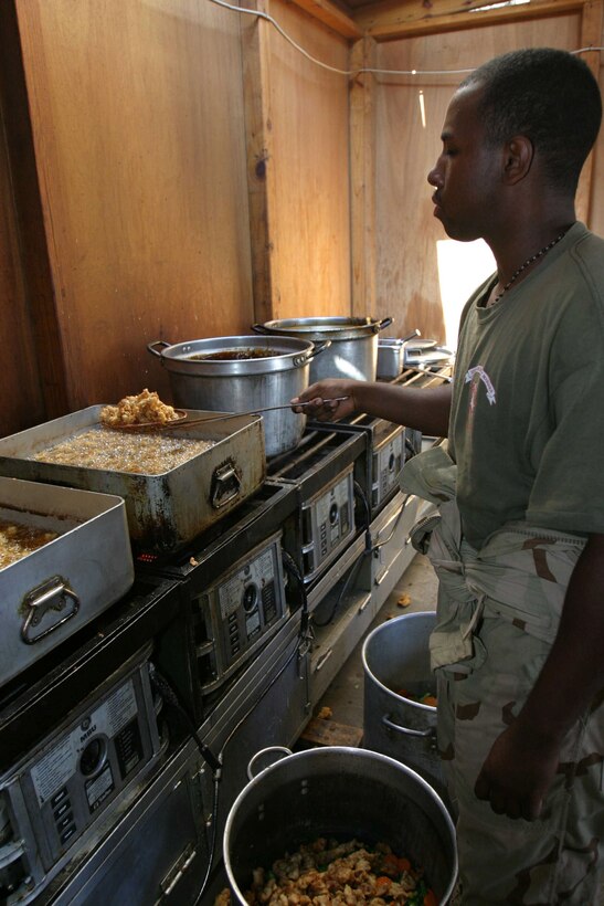 HADITHA DAM, Iraq - Lance Cpl. Martell O. Rogers, St. Louis native and assistant mess chief for 3rd Battalion, 1st Marine Regiment, prepares chicken for a stir fry meal here Sept. 30. Rogers and other cooks in the battalion prepare meals for more than 1,400 people here daily.