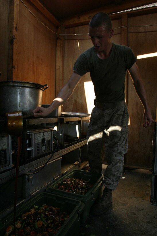 HADITHA DAM, Iraq - Corporal Ryan L. Pennington, a Phoenix native and field mess chief for 3rd Battalion, 1st Marine Regiment, pours teriyaki sauce on top of stir fry ready to be served here Sept. 30. Pennington and other cooks in the battalion prepare meals for more than 800 pounds of food per meal here daily.