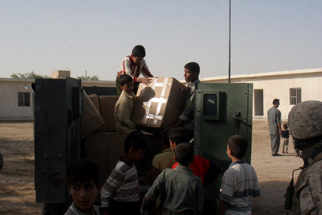 051018-M-2607O-001 KARMAH, Iraq -- Students from the Thorouh Al Aashreen Primary School help unload backpacks that were handed out during the opening ceremony by the Karmah Police Chief Lt. Col. Dalouf and the school headmaster Oct. 18.  The Marines of Team Two 6th Civil Affairs Group provided the backpacks for the ceremony.