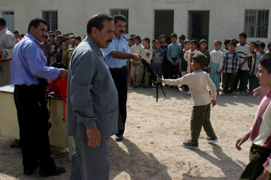 051018-M-2607O-003 KARMAH, Iraq -- Lieutenant Col. Dalouf and one of his officers from the Karmah Police Station hand out backpacks to the Thorouh Al Aashreen Primary School students during the official opening ceremony Oct. 18.  Approximately 800 students are attending the school now that it is officially open.
