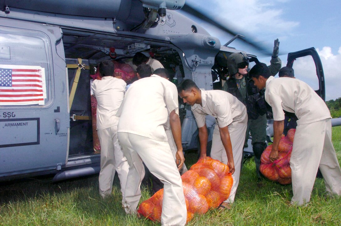 DAMBULA, Sri Lanka -- Airman 1st Class Emily Starcher helps Sri Lankan relief workers unload vegetables from an HH-60G Pave Hawk helicopter during an Operation Unified Assistance mission here. She is a flight engineer assigned to the 33rd Rescue Squadron at Kadena Air Base, Japan. The Kadena Airmen are helping bring food, medicines and supplies to people affected by the Dec. 26 tsunamis. (U.S. Air Force photo by Master Sgt. Val Gempis)