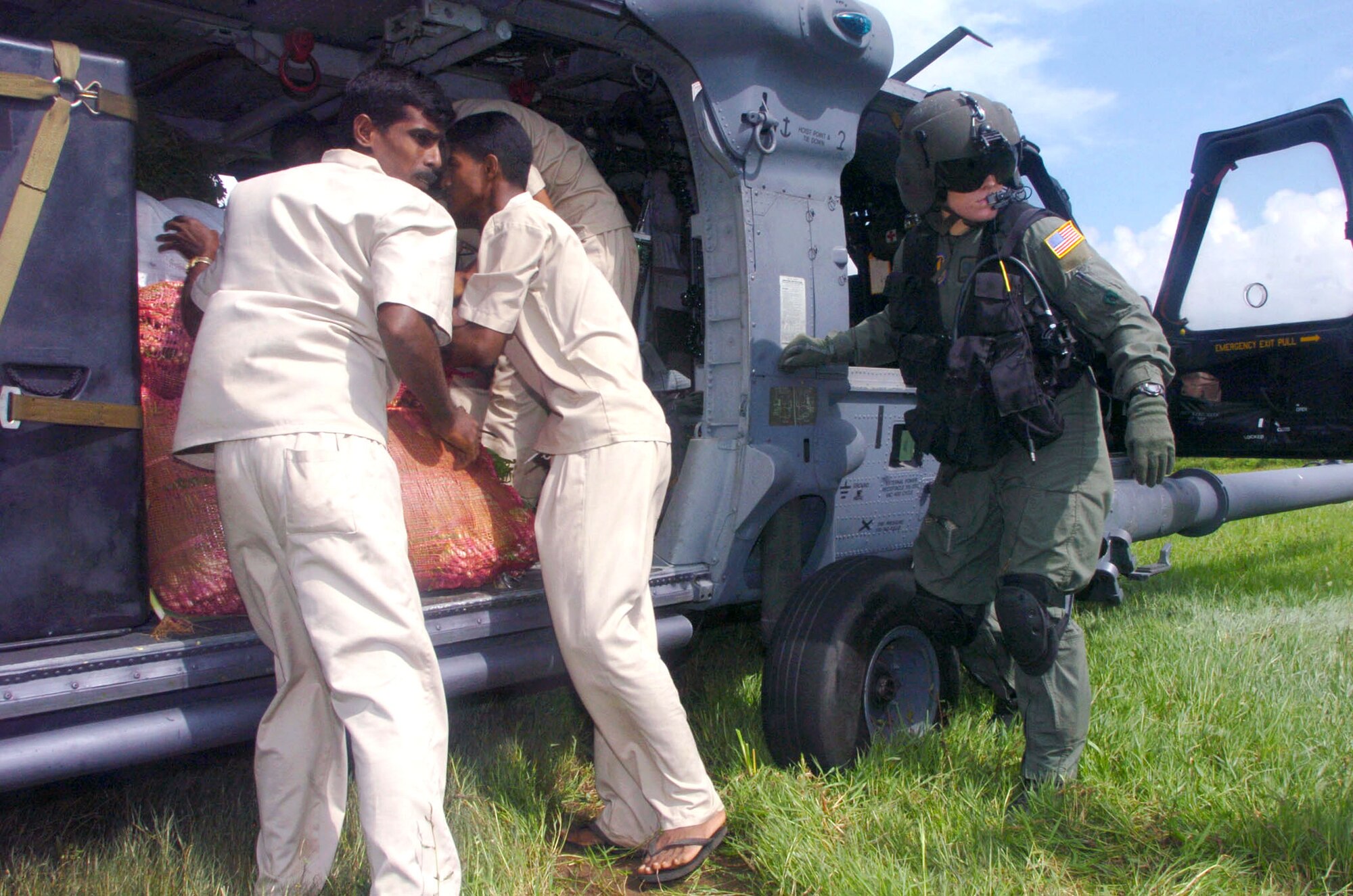 DAMBULA, Sri Lanka -- Airman 1st Class Emily Starcher helps Sri Lankan relief workers unload vegetables from an HH-60G Pave Hawk helicopter during an Operation Unified Assistance mission here.  She is a flight engineer assigned to the 33rd Rescue Squadron at Kadena Air Base, Japan.  The Kadena Airmen are helping bring food, medicines and supplies to people affected by the Dec. 26 tsunamis. (U.S. Air Force photo by Master Sgt. Val Gempis)