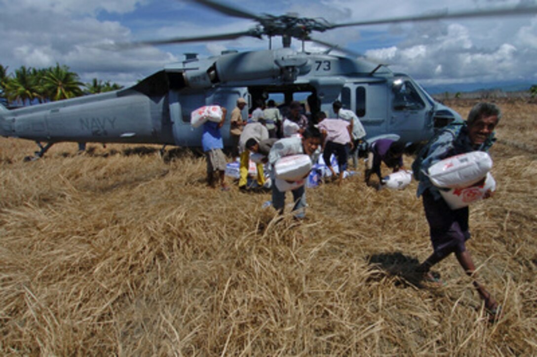 Indonesians run out from under the rotor blades as they offload relief supplies from a U.S. Navy MH-60S Knighthawk helicopter in Sumatra, Indonesia, on Jan. 13, 2005. The Knighthawk is assigned to Helicopter Squadron 11 from the USS Bonhomme Richard (LHD 6) Expeditionary Group which is operating in the Indian Ocean off the coasts of Indonesia and Thailand in support of Operation Unified Assistance. 